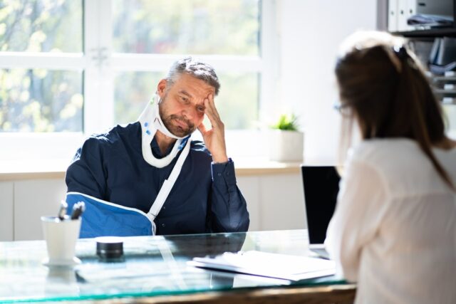 Man with cervical collar talking with his personal injury lawyer