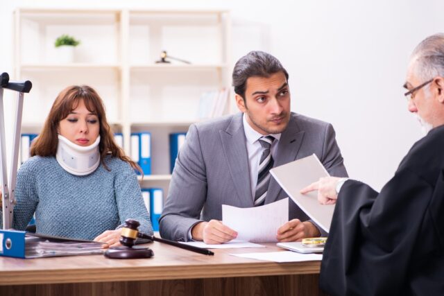 Woman with cervical collar and her personal injury lawyer discussing their case with a judge. 