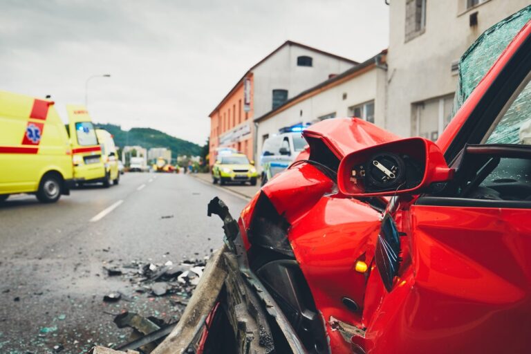 Severely damaged uber vehicle after an accident, with ambulances visible in the background.