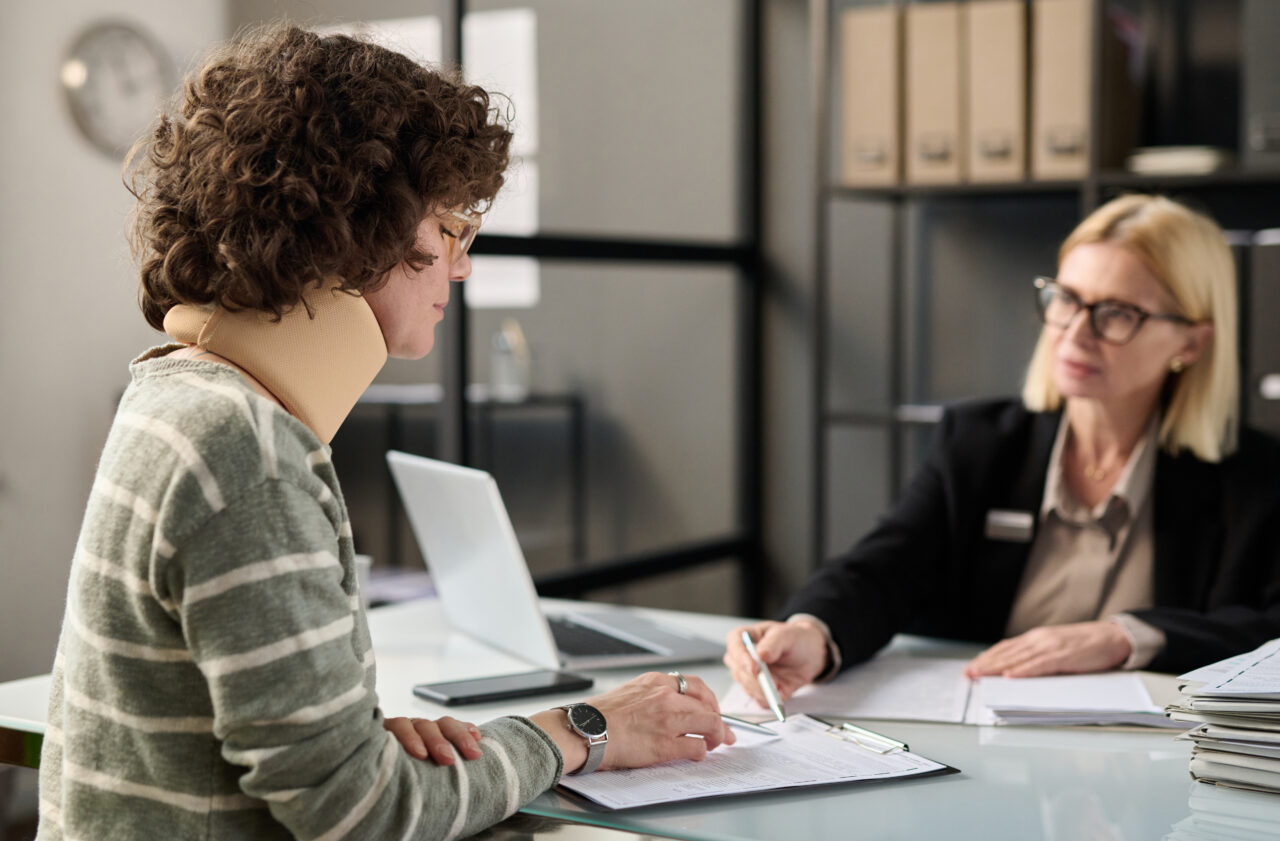Injured woman consulting with a lawyer in an office setting.
