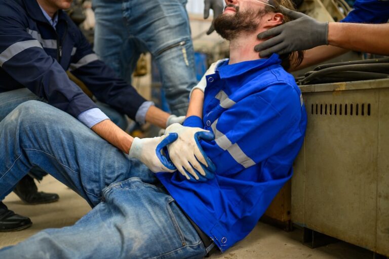 Injured worker receiving assistance from colleagues at a workplace accident scene, emphasizing the importance of hiring experienced work injury lawyers.