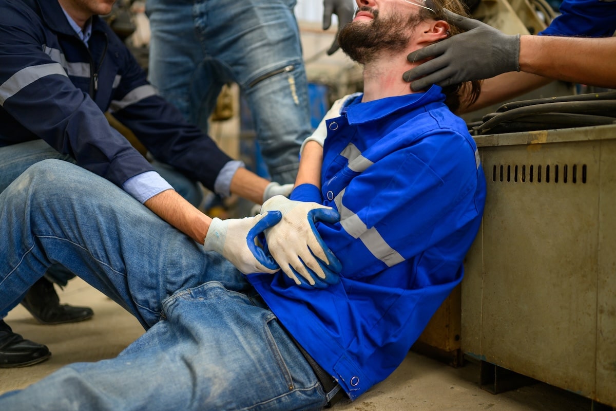 Injured worker receiving assistance from colleagues at a workplace accident scene, emphasizing the importance of hiring experienced work injury lawyers.