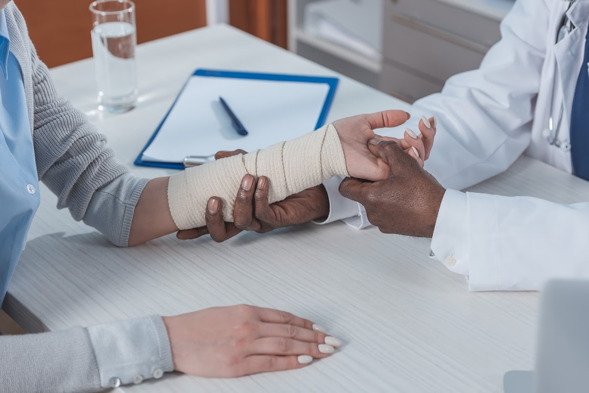 A doctor examines a patient's bandaged wrist, highlighting the importance of medical attention in workers' compensation claims.